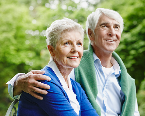 portrait of senior couple with green trees in background planning for retirement