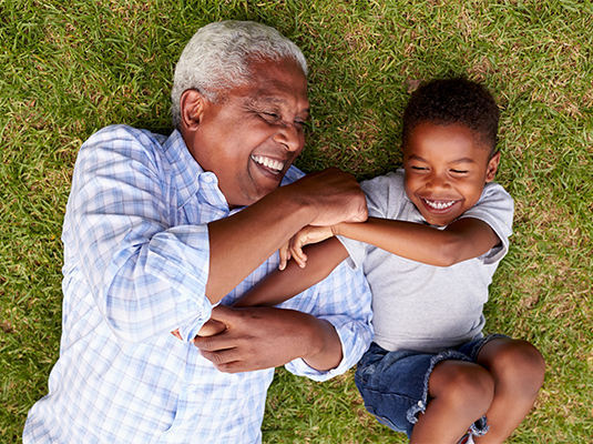 senior and grandchild laying on gras laughing tax-deferred annuity dotson financial michigan